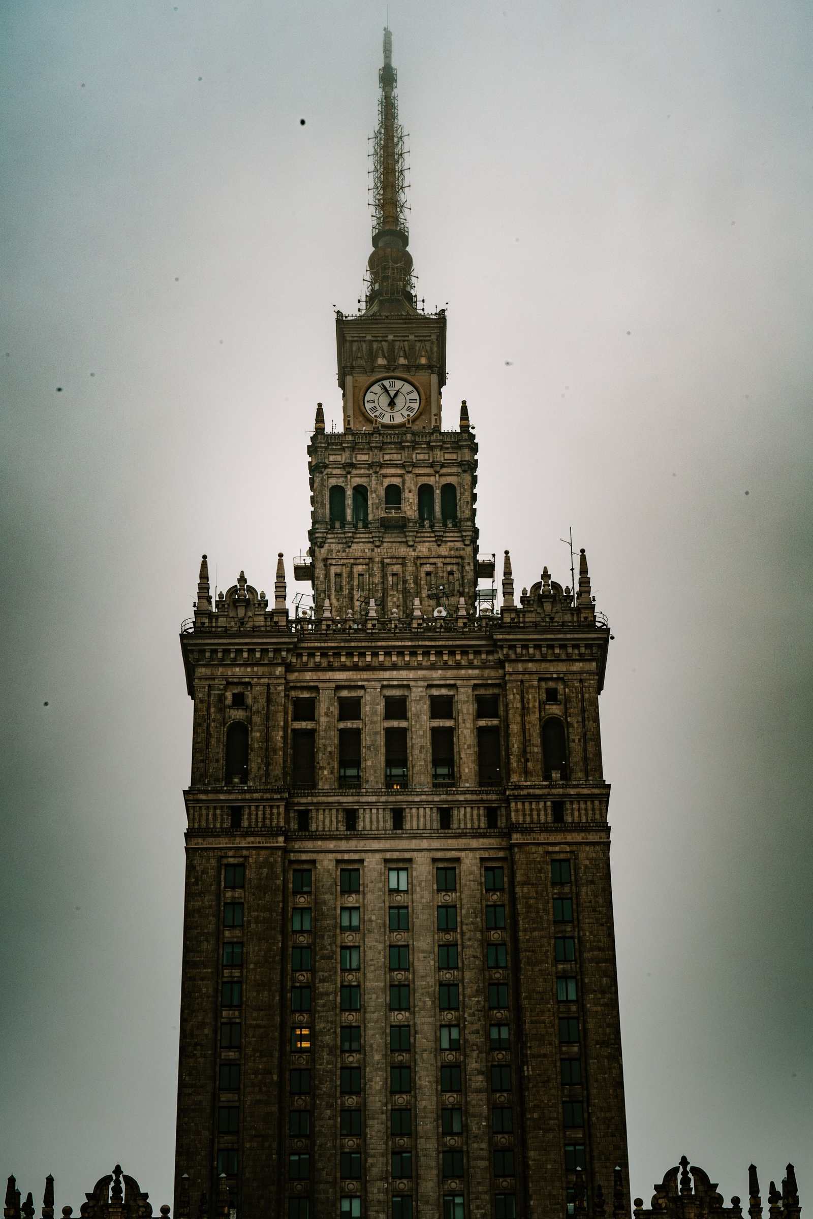 Pałac Kultury i Nauki fotografowany frontalnie od dołu, cała wieża z iglicą na tle pochmurnego nieba.