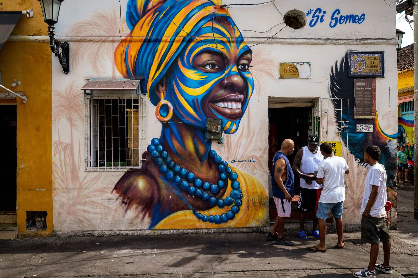 Kolorowy mural przedstawiający kobietę z niebiesko-żółtym malowaniem twarzy, Cartagena.